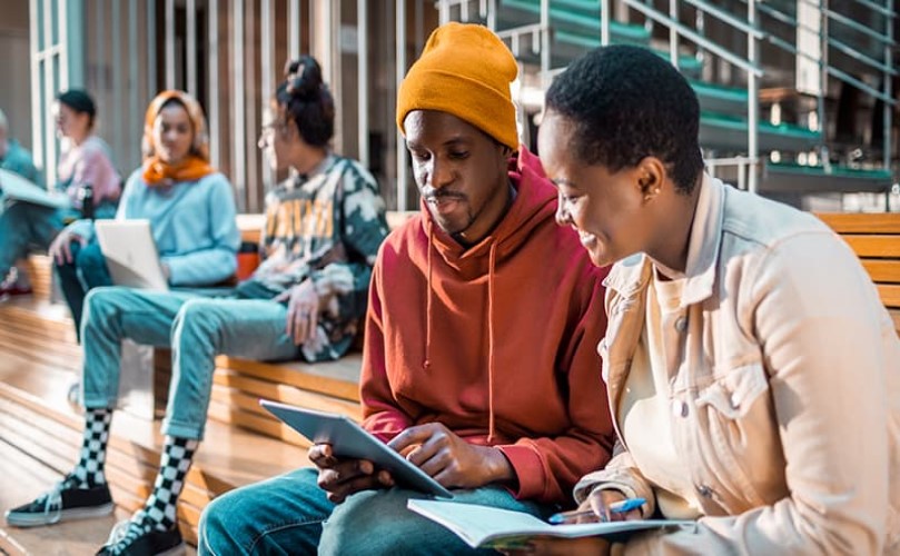 A man and a woman laughing while looking at a tablet