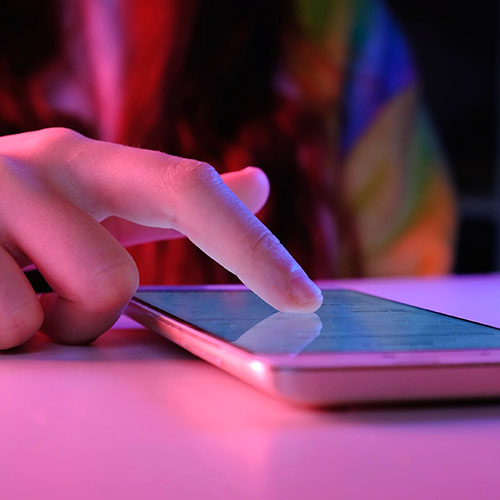 Finger pointing to mobile phone screen in pink neon lit shot
