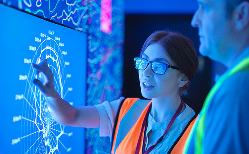 Image of a woman and a man talking in front of a monitor