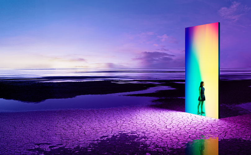 Woman before a colorful light door in a barren, purple landscape.