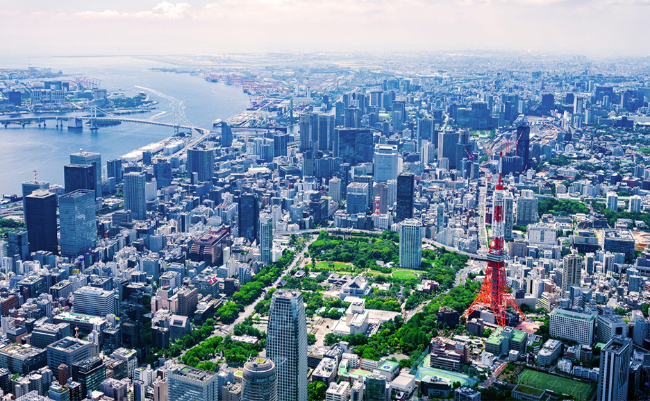 Aerial view of the cityscape featuring Tokyo Tower surrounded by high-rise buildings and Tokyo Bay.