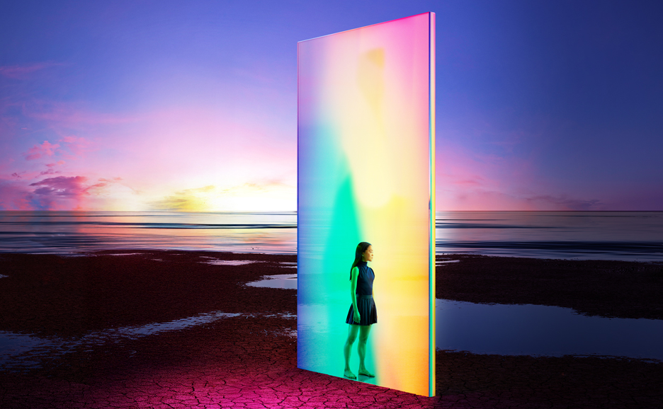 Woman by rainbow light wall on sunset beach