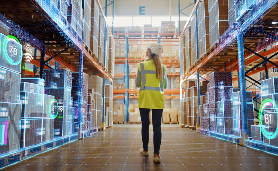 mployee navigating a well-lit warehouse, focused on data displayed on her device.