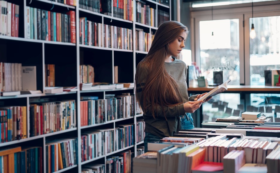 A woman browsing books in a library or bookstore.
