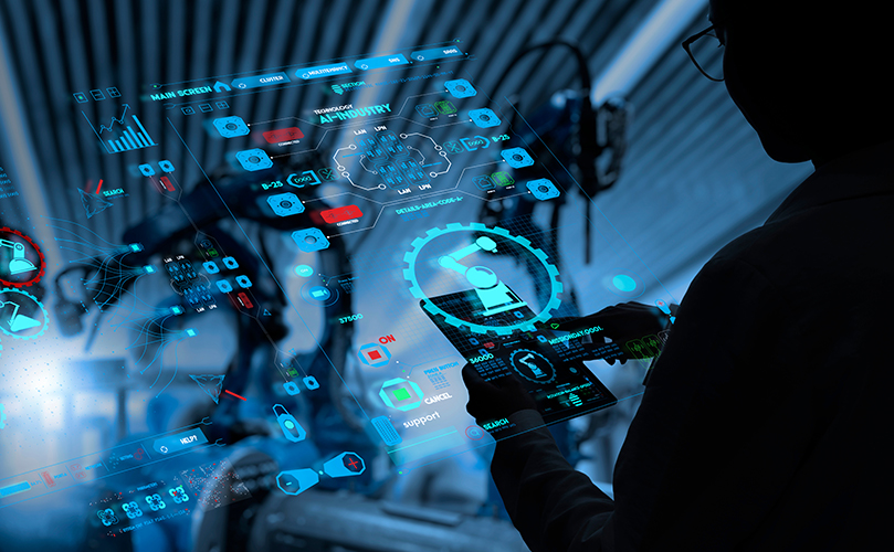 A person using a tablet to interact with digital control panels in an industrial environment.