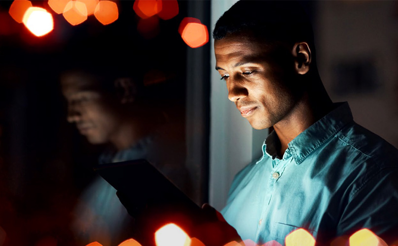 Shot of a young man using a tablet during a late night